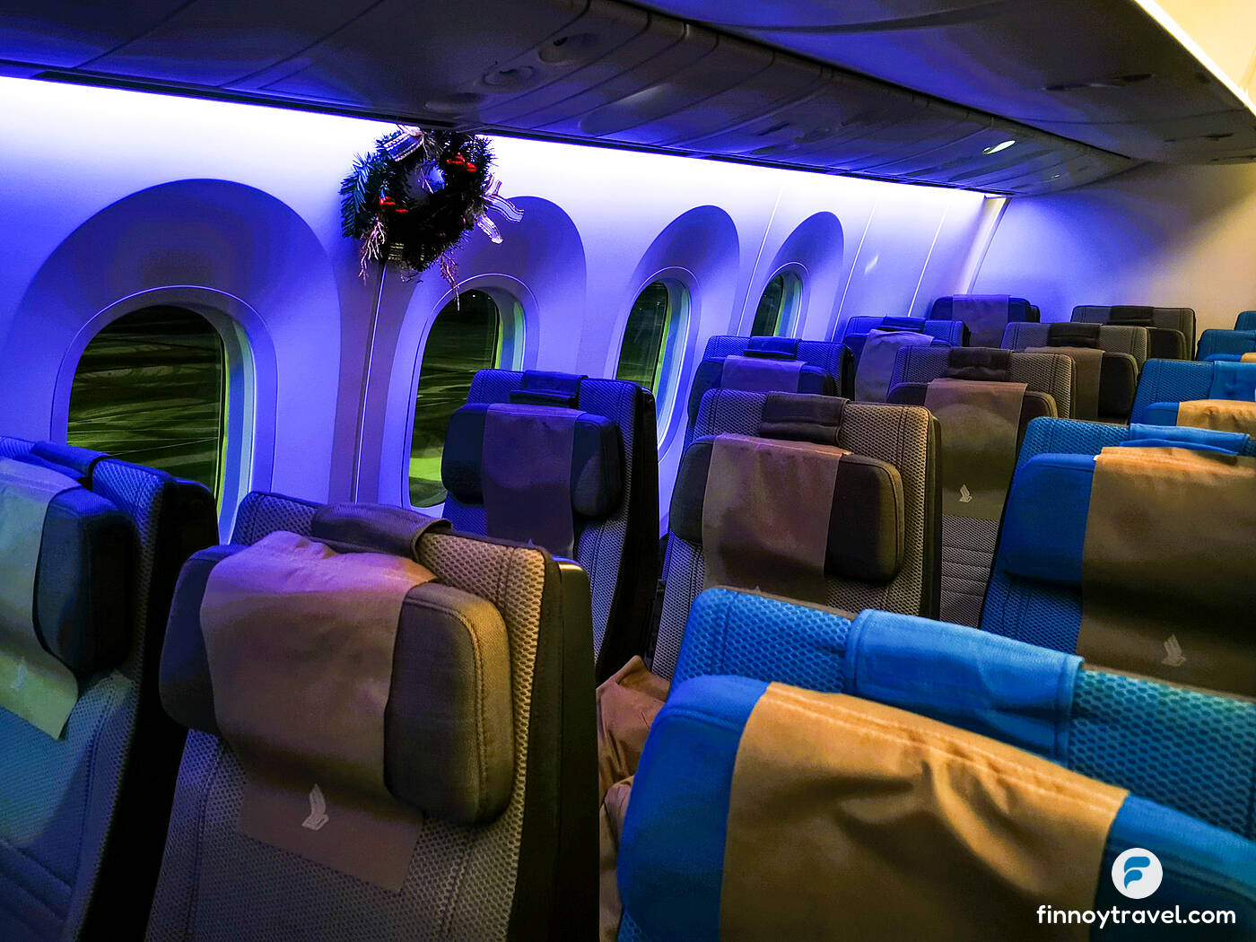 Airplane seats of Singapore Airlines with some Christmas decorations by the windows.