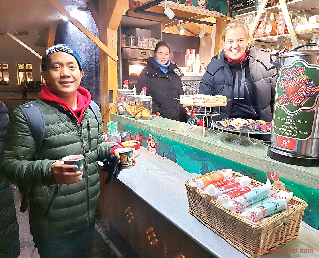 タリン旧市街のクリスマスマーケットでグロギを売る、にこやかな店主