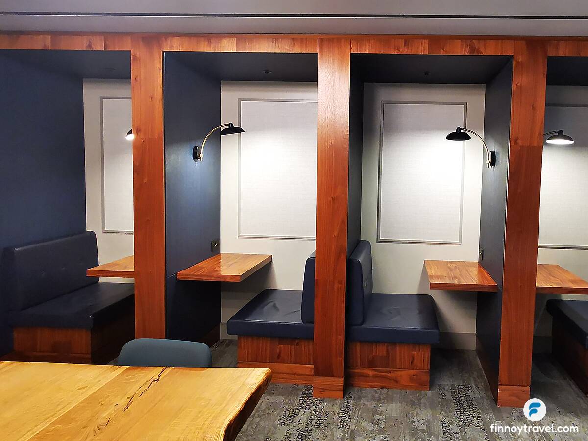 Cadeiras azuis e mesas de madeira no Centurion Lounge no Aeroporto de Heathrow.