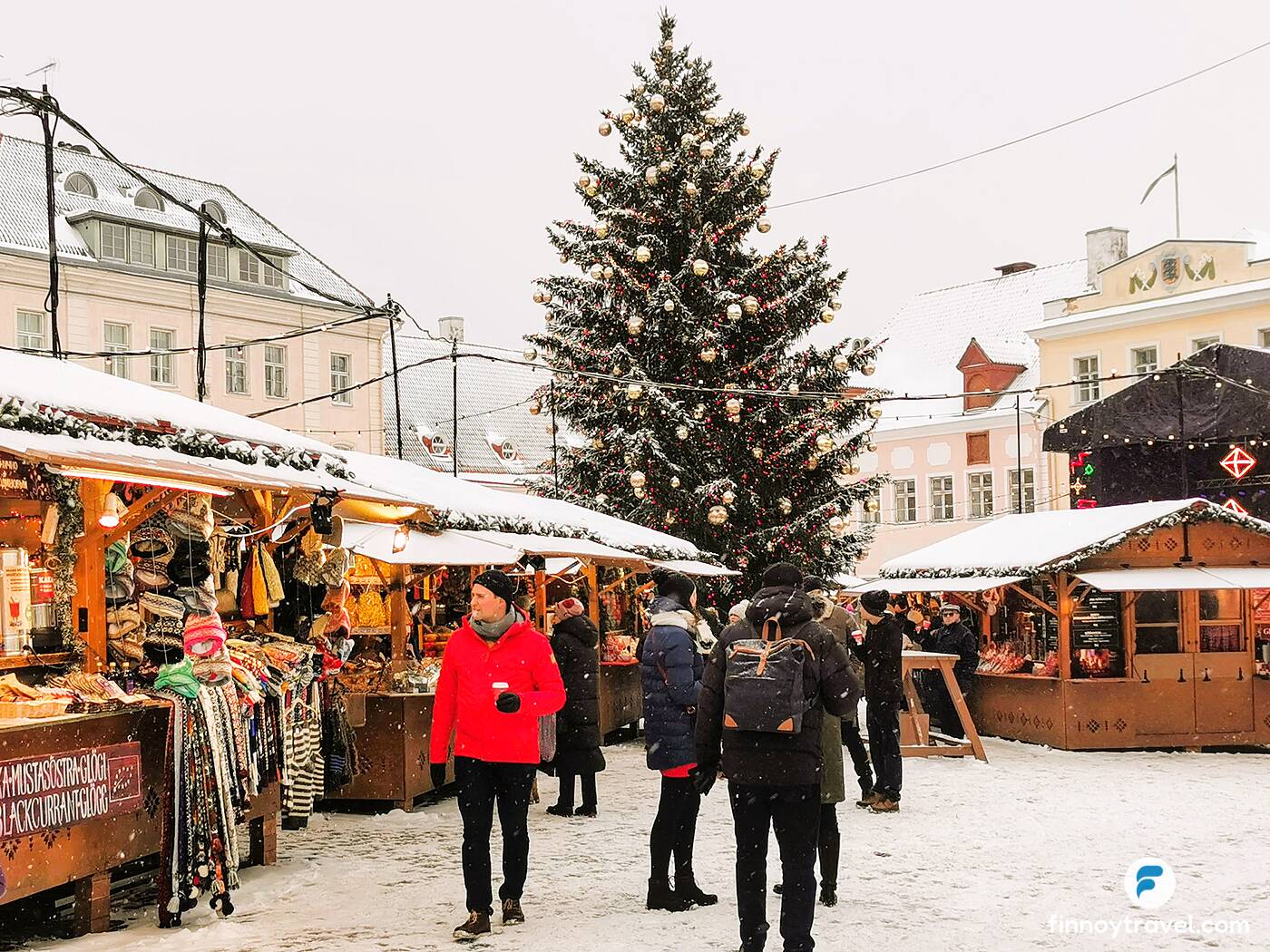 Visitantes caminhando ao lado da &aacute;rvore de Natal no Mercado de Natal de Tallinn